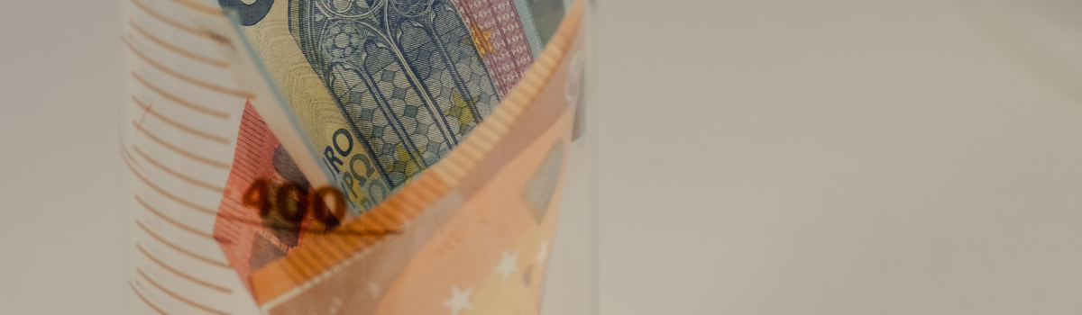 Geldscheine stecken in einem Maßkolben aus Glas.